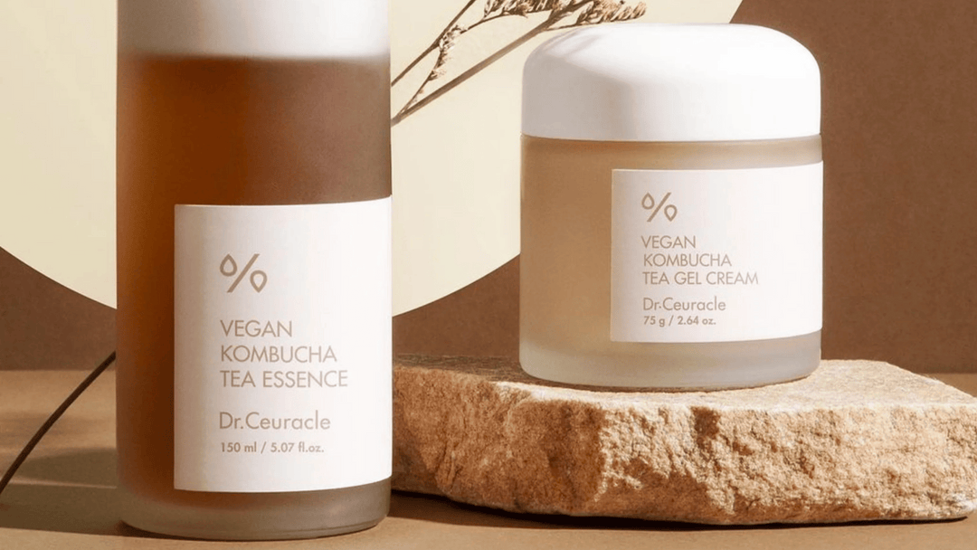 Dr. Ceuracle Vegan Kombucha Tea Essence och Tea Gel Cream i eleganta frostad glasförpackning, placerade på en stenplatta med naturlig belysning och jordnära bakgrund.