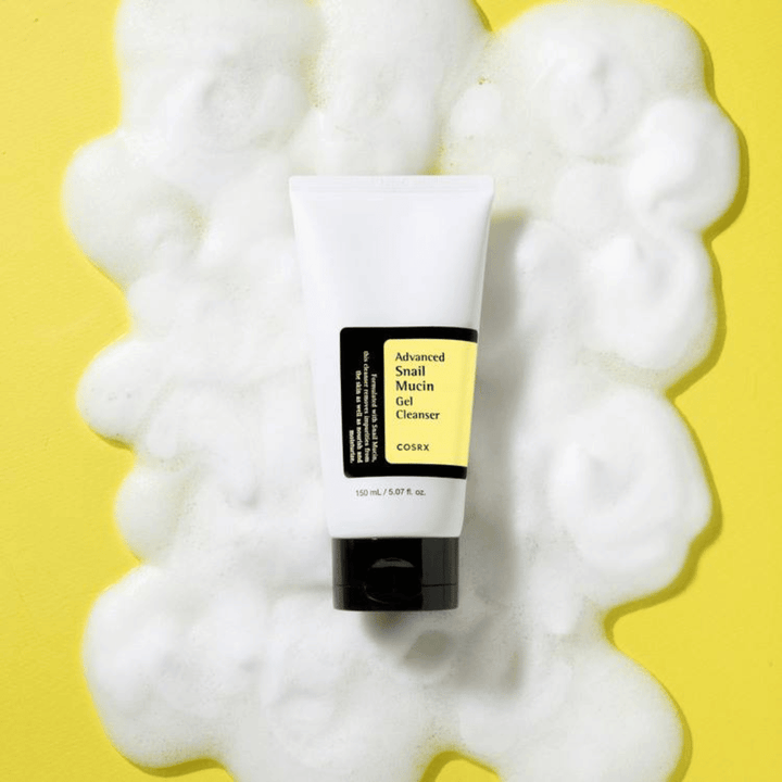 COSRX Advanced Snail Mucin Gel Cleanser 150 ml surrounded by abundant foam on a yellow background – mild Korean face wash with snail mucin for hydration and radiance.