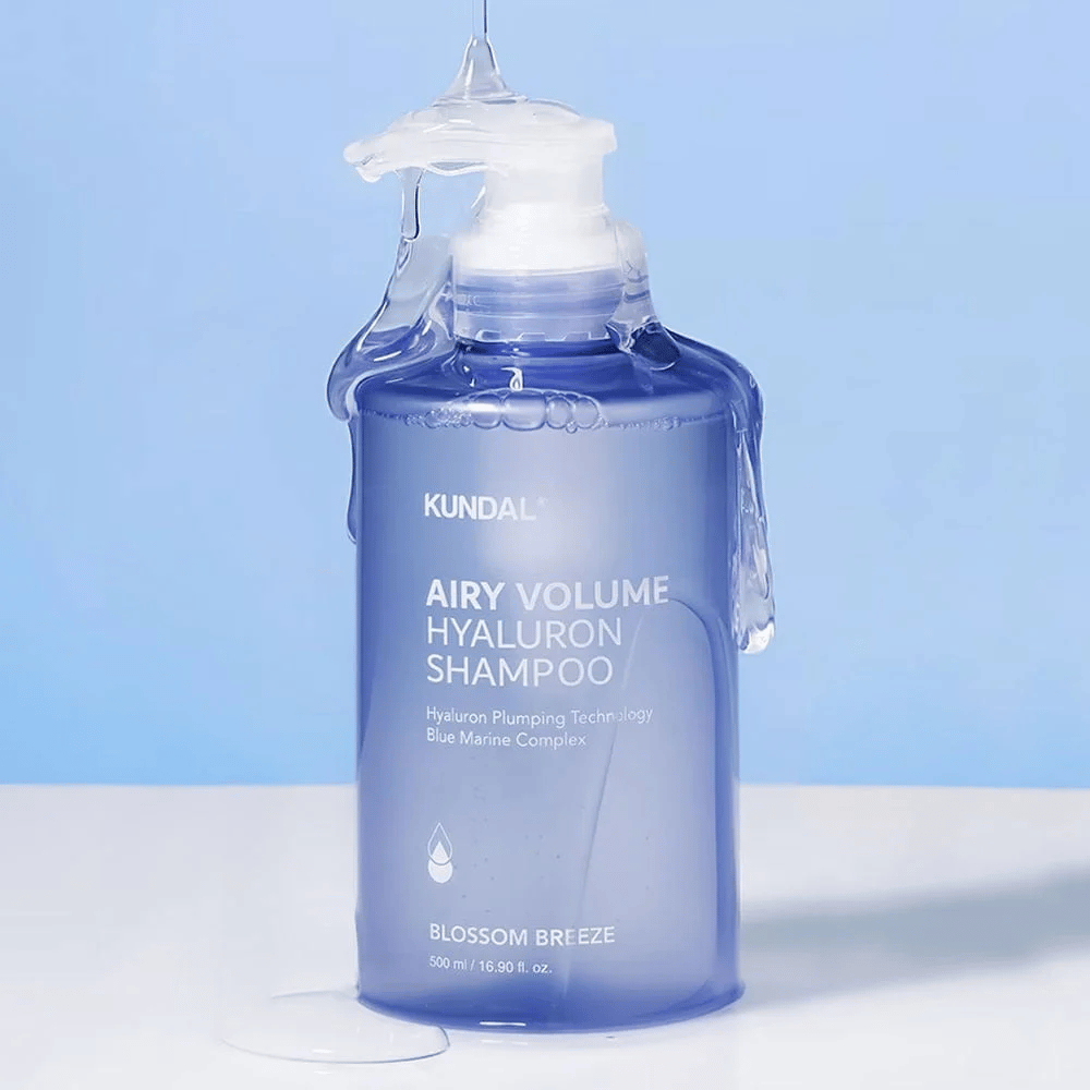 KUNDAL Airy Volume Hyaluron Shampoo Blossom Breeze in blue pump bottle, with hyaluron and Blue Marine Complex, photographed with running water.
