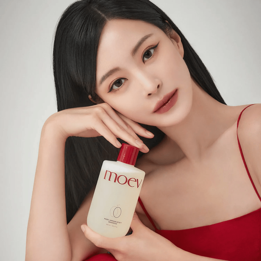 Woman with long, shiny hair holds MOEV Annurcatin Shampoo – a Korean shampoo that moisturizes, strengthens, and protects hair with natural ingredients.