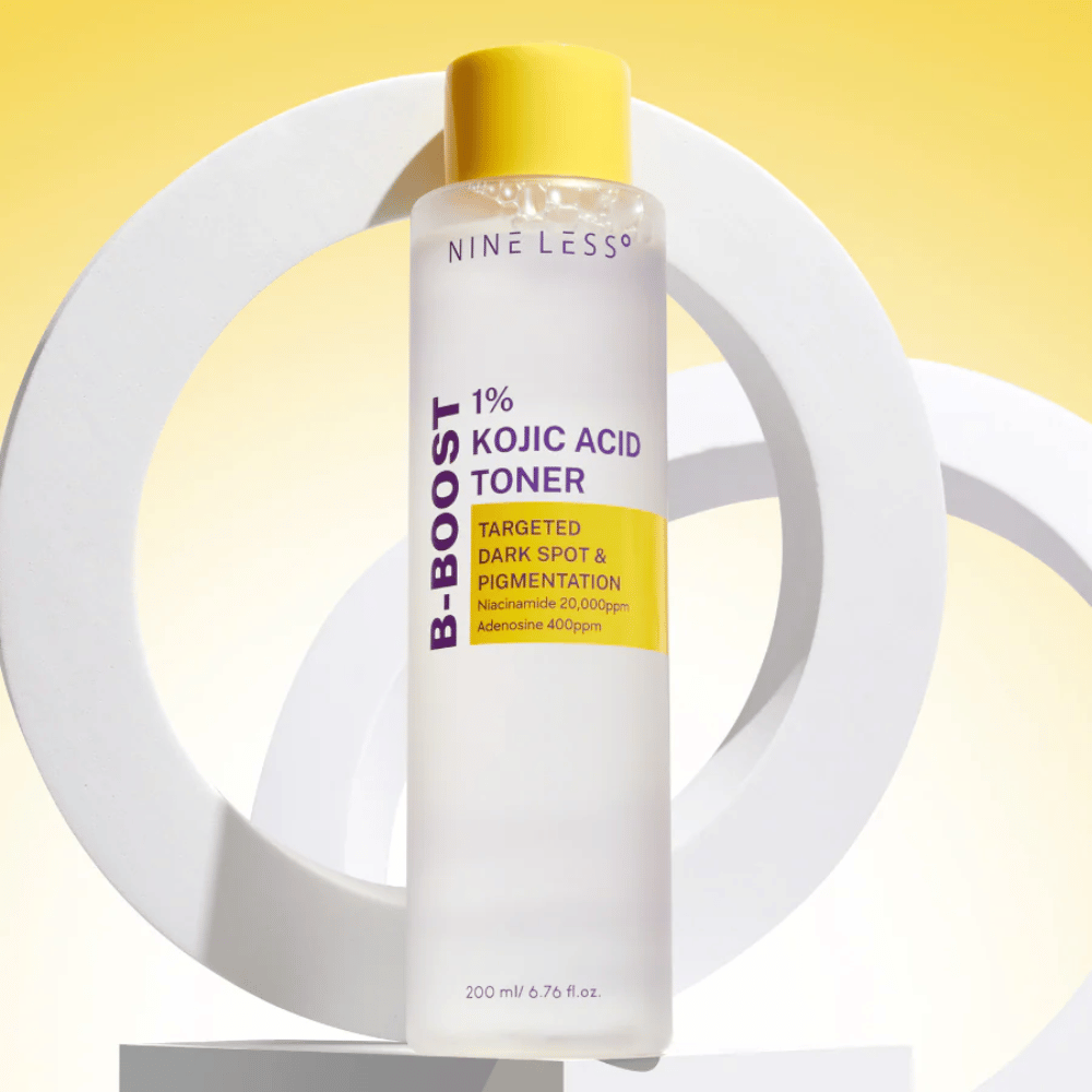 NINE LESS B-Boost 1% Kojic Acid Toner standing against a yellow background with the text "Targeted Dark Spot & Pigmentation". Skin tone evening toner with niacinamide and adenosine.