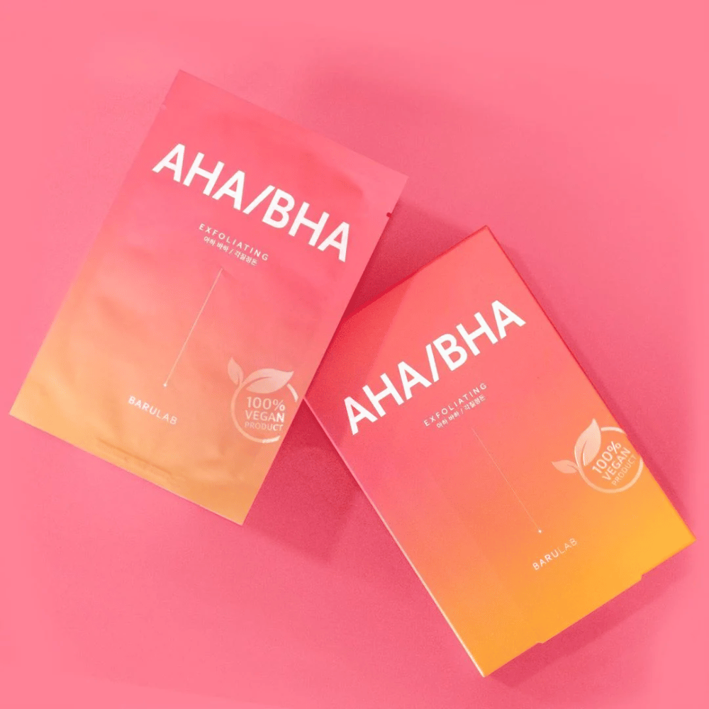 Two products from BARULAB, one in a bag and one in a box, both labeled with "AHA/BHA" and "Exfoliating" against a pink background. The products are marked as "100% Vegan Product".