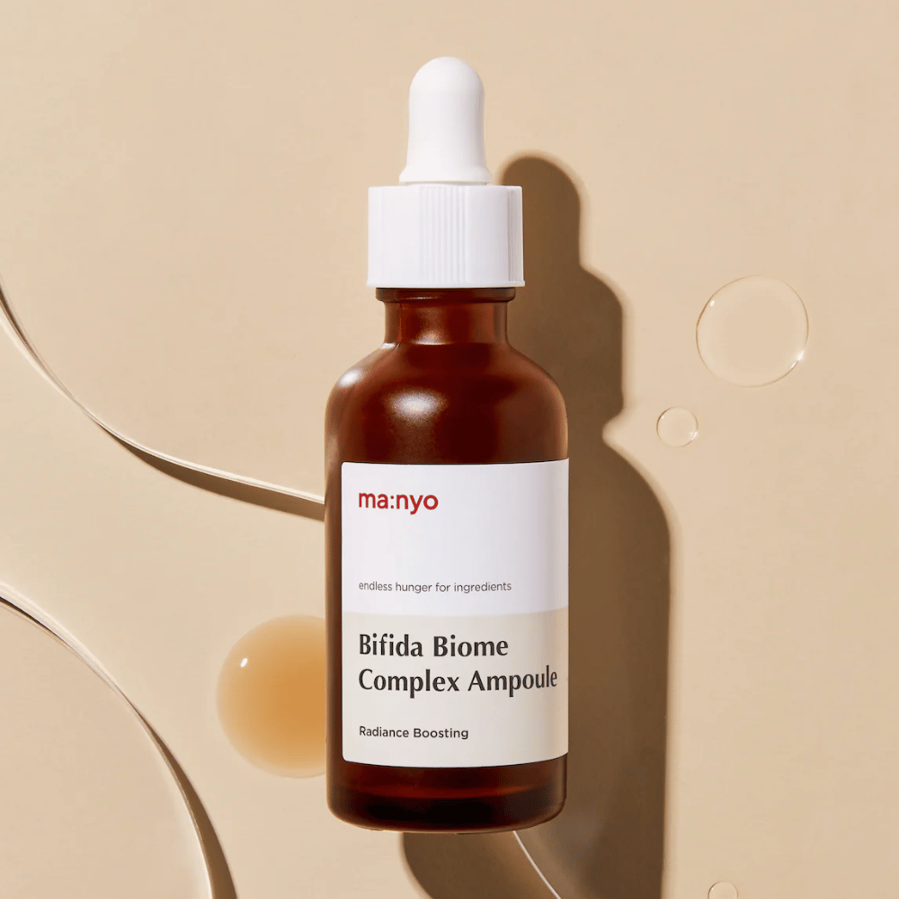 Stylish product image of ma:nyo Bifida Biome Complex Ampoule focusing on the bottle design and serum drops in the background.