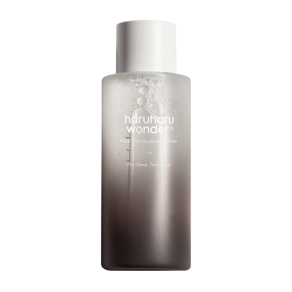A bottle of haruharu wonder Black Rice Hyaluronic Toner with a gray to white color gradient and water droplets on the surface, against a white background.