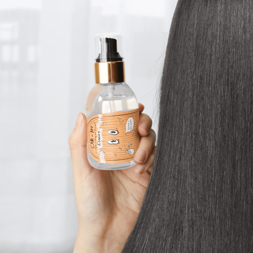 Person holding CER-100 Hair Essence next to long, shiny hair to show softness and care.