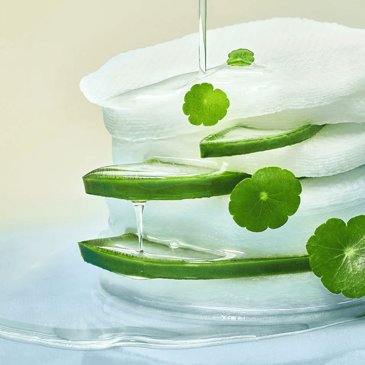 Close-up of aloe vera slices, hydrating toner pads, and centella asiatica leaves. The gel drips between the ingredients to illustrate soothing, cooling, and hydrating properties.