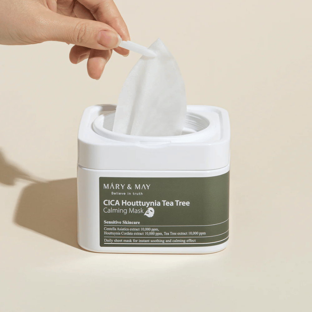 Hand pulling up a sheet mask from Mary & May Cica Houttuynia Tea Tree Calming Mask jar – soothing face mask for sensitive skin with Cica and Tea Tree extract.