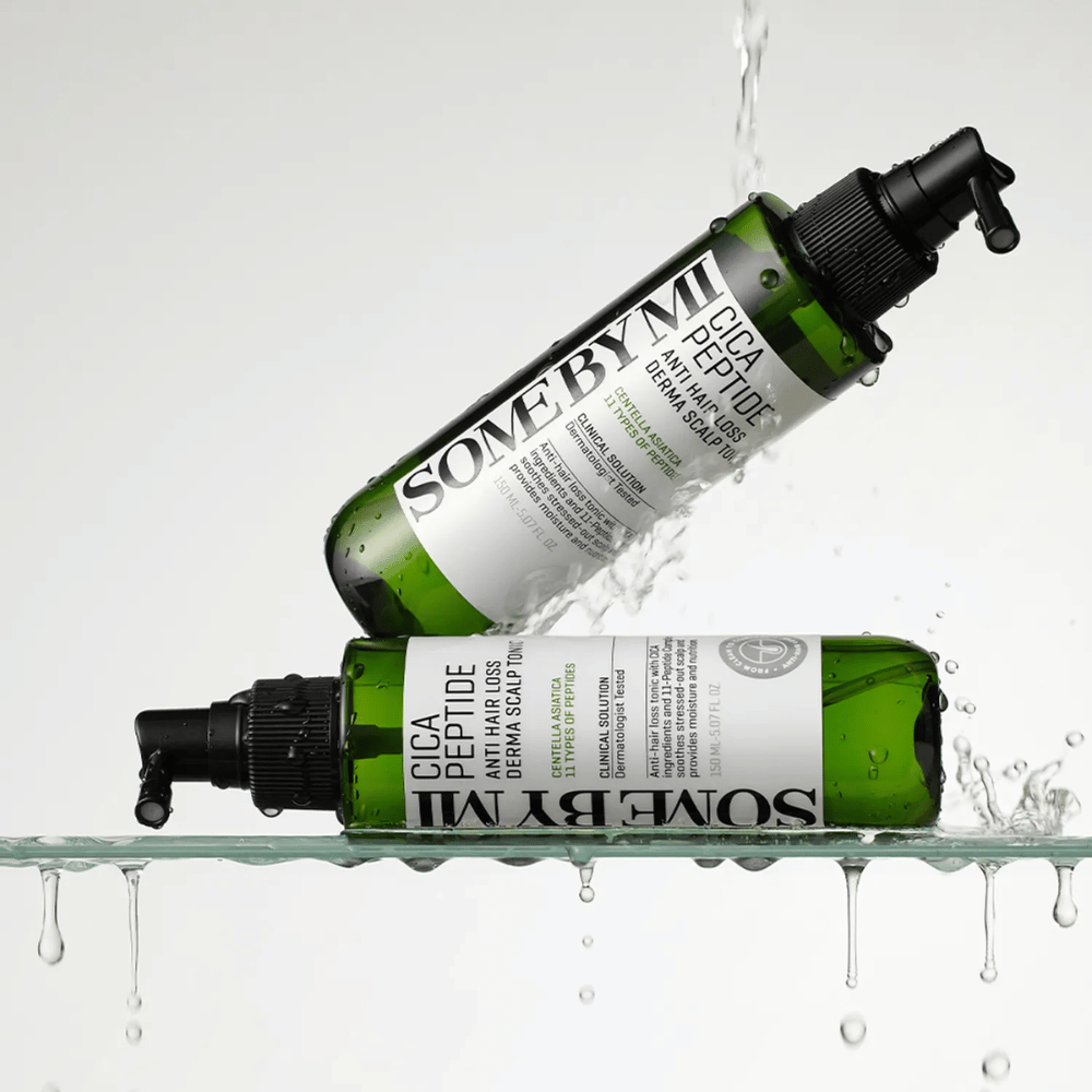 Two bottles SOME BY MI Cica Peptide Anti Hair Loss Derma Scalp Tonic lie in and above water with splashing droplets, green bottles with black spray nozzle and white label.