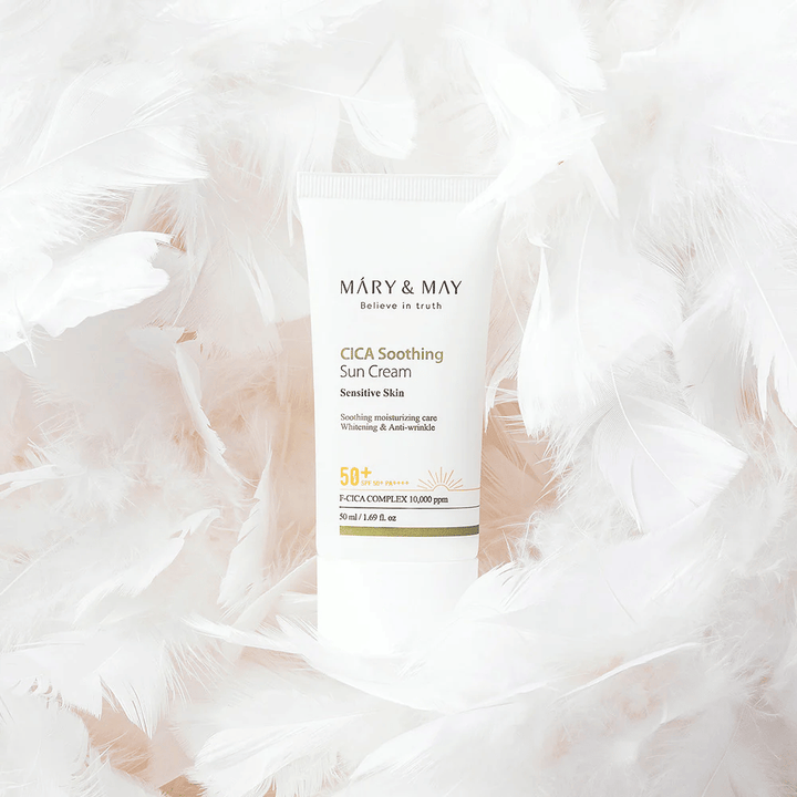 Mary&May CICA Soothing Sun Cream surrounded by soft white feathers. The image conveys a sense of gentleness, comfort, and a lightweight formula adapted for sensitive skin.