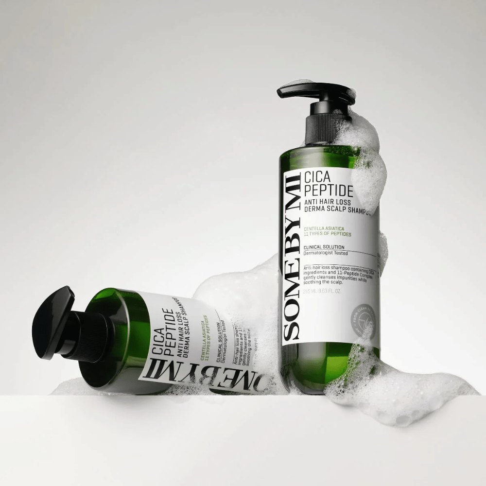 Two bottles of SOME BY MI Cica Peptide Anti Hair Loss Derma Scalp Shampoo covered in foam, standing and lying against a white background.