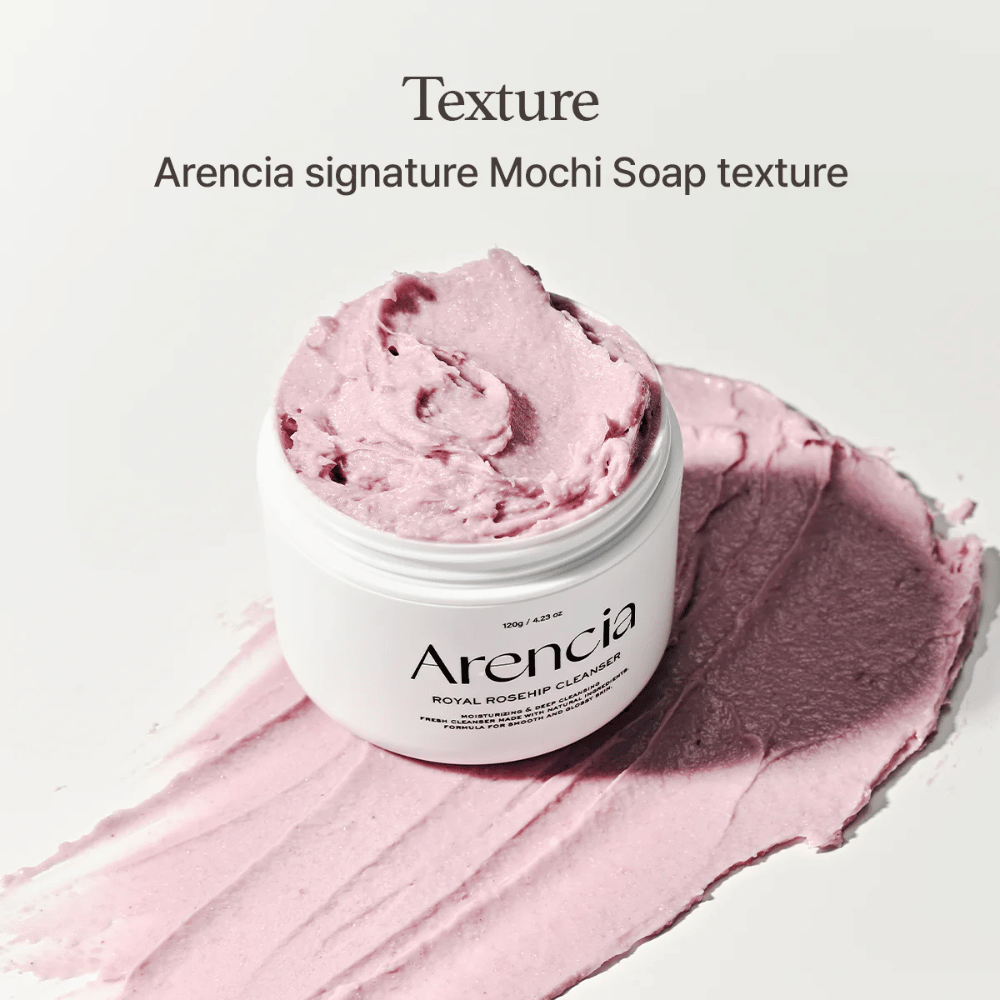 Jar with Arencia Royal Rosehip Cleanser visible on top of a smeared pink cleanser with a mochi-like texture. The text above describes the product as Arencia's signature texture.