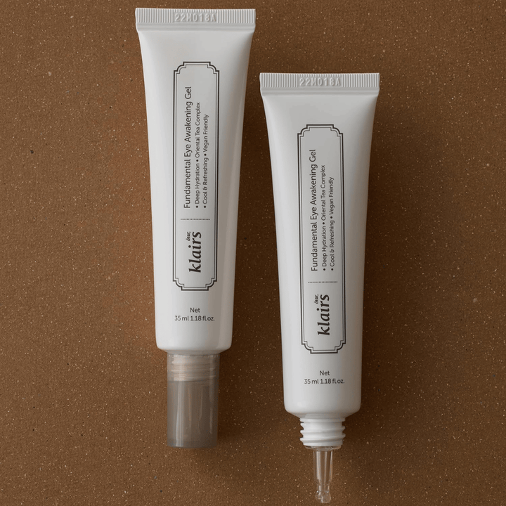 Product image showing Klairs Fundamental Eye Awakening Gel in two versions – a closed tube and an open tube that highlights the narrow applicator tip. The packaging has a minimalist white design and emphasizes the product’s focus on hydration, a cooling sensation, and refreshing care for the eye area.