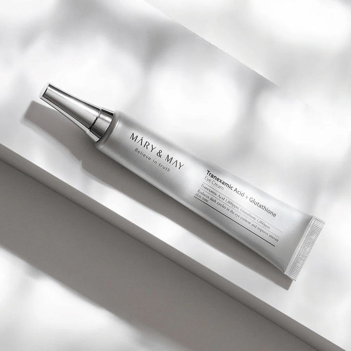 Close-up of Mary&May Tranexamic Acid + Glutathione Eye Cream with metal applicator, developed to brighten dark circles and even out the skin tone around the eyes.