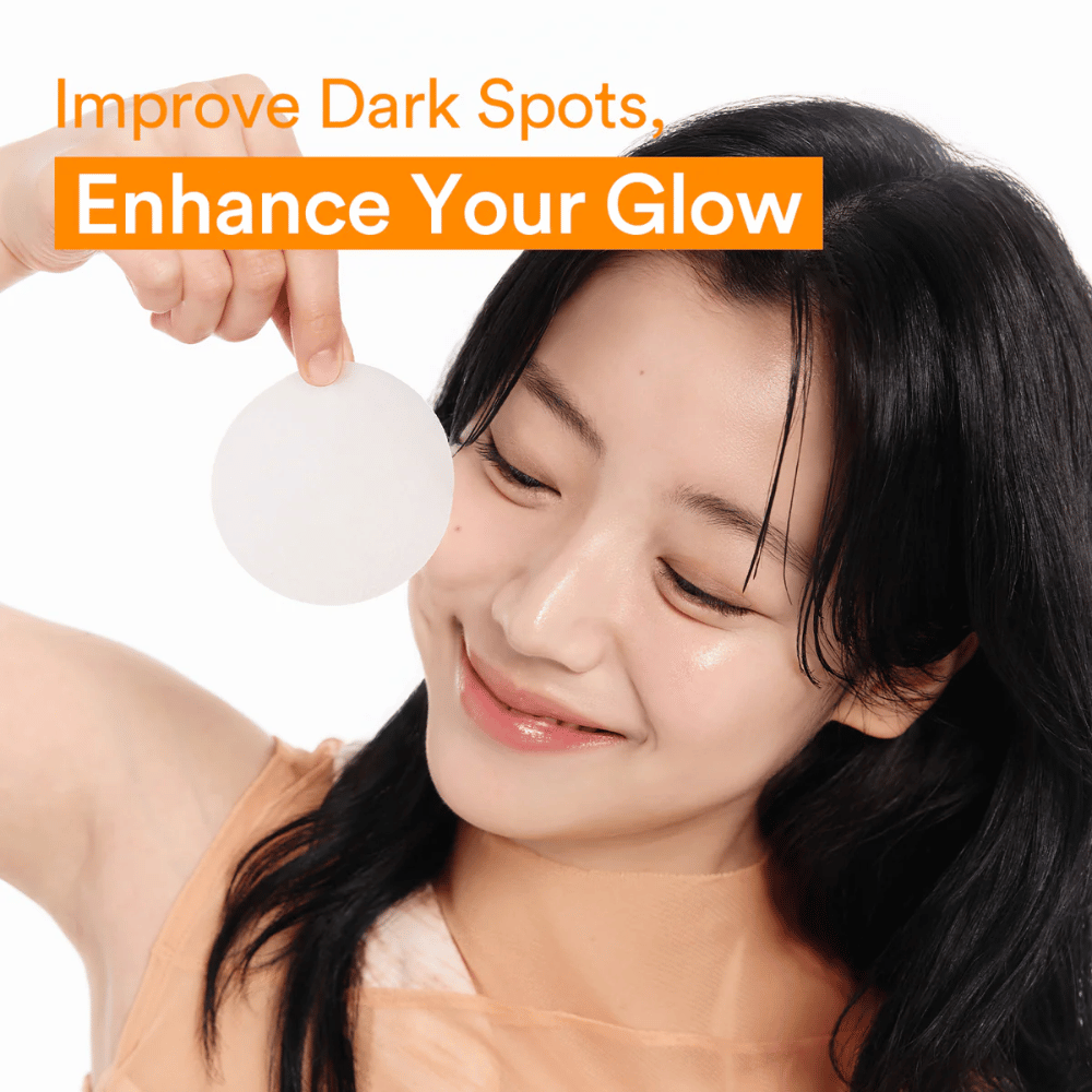 Woman holding up a glow-enhancing toner pad to reduce dark spots and give clearer skin.