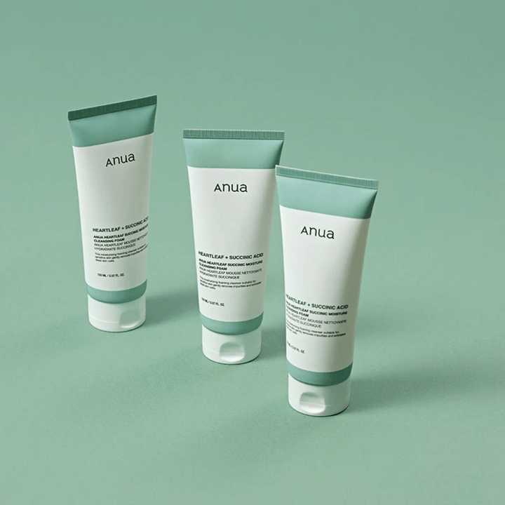 Three packages of Anua Heartleaf + Succinic Acid Moisture Cleansing Foam presented against a light green background. The image highlights the product's clean and minimalist design and gives a professional impression of the product line.