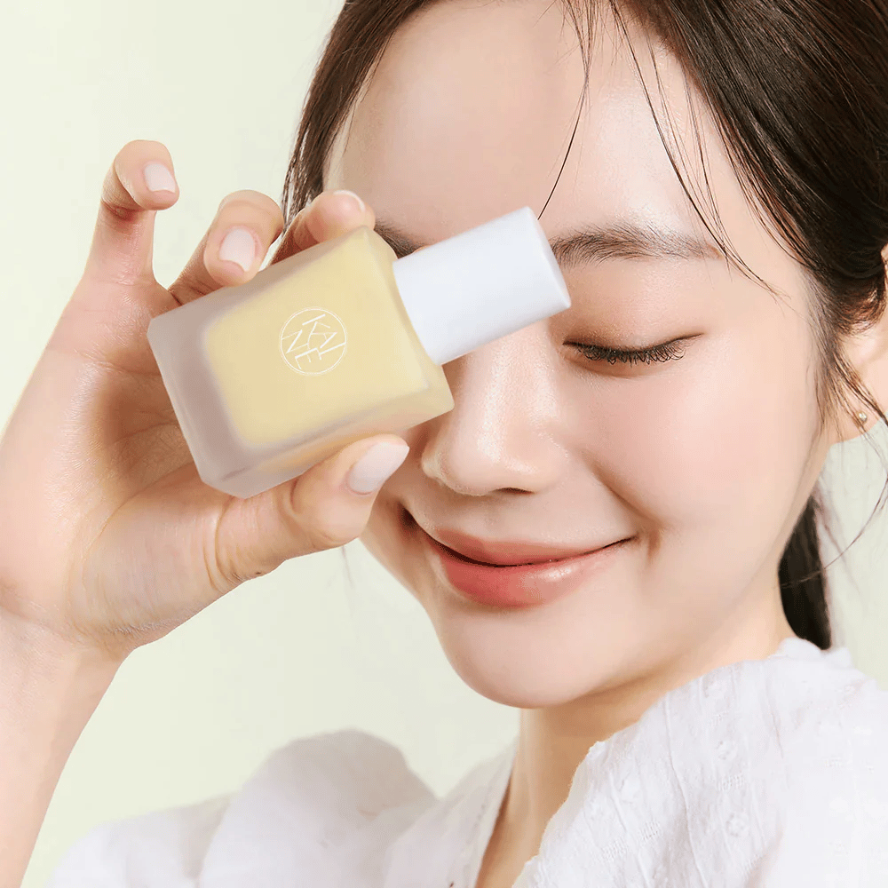 A woman is holding a KAINE Vita Drop Serum 30ml bottle.