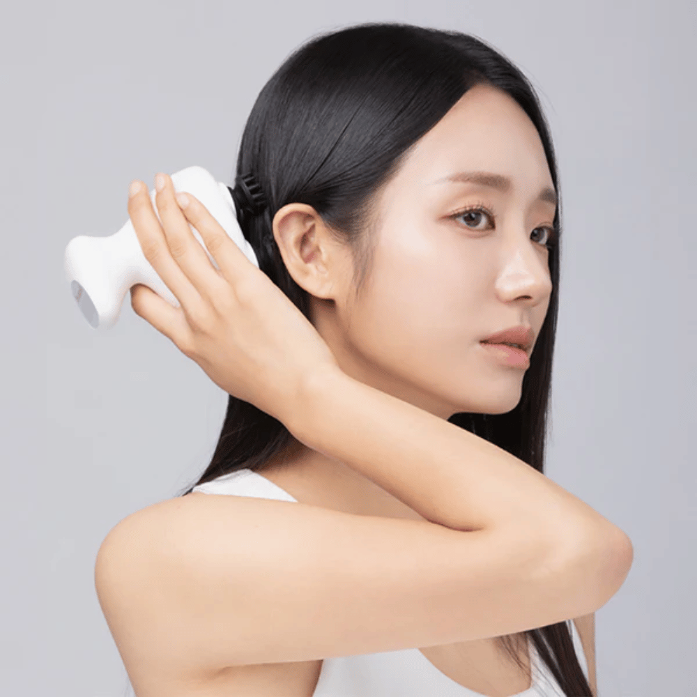 Model uses Beaund Lift Head Spa directly against the scalp behind the ear. The image demonstrates how the device is used to massage the scalp and provide pleasant stimulation.