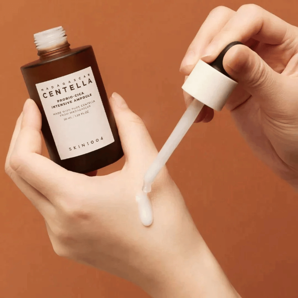 Hands using dropper to dose "Madagascar Centella Probio-Cica Intensive Ampoule" from SKIN1004.