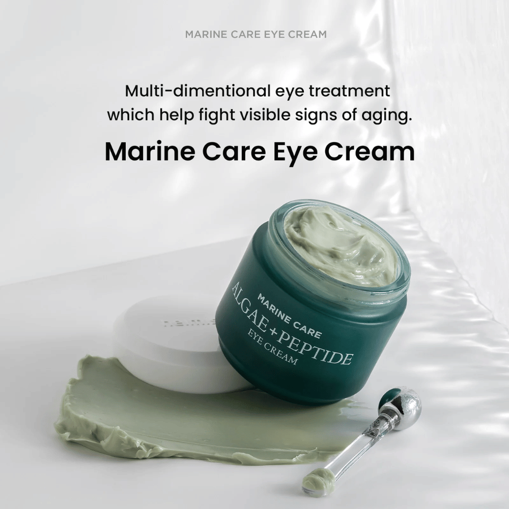 Heimish Marine Care Algae + Peptide Eye Cream in an open jar with greenish cream. The cream is spread next to the jar and an applicator lies nearby. The product combats signs of aging and provides intense hydration.