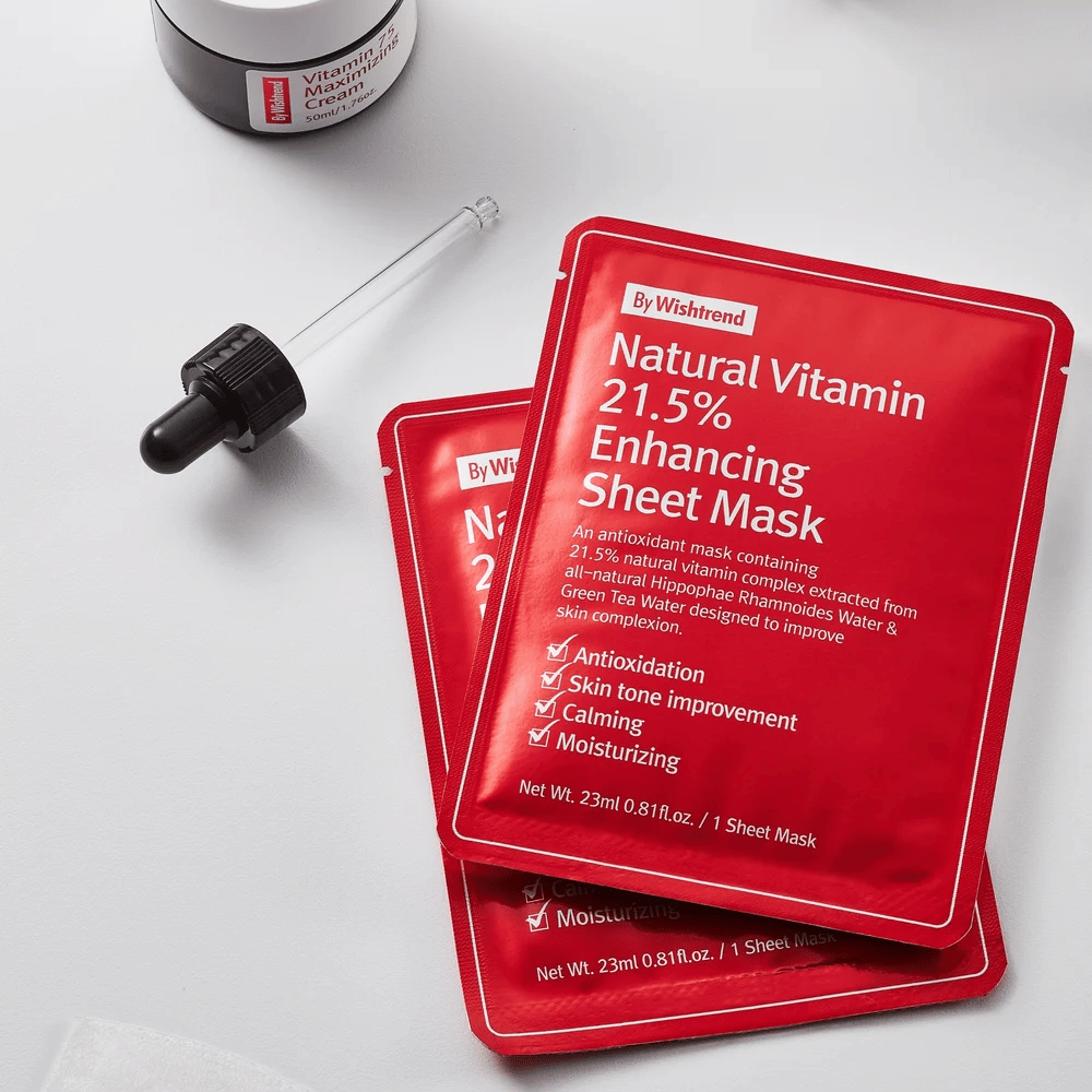By Wishtrend Natural Vitamin 21.5% Enhancing Sheet mask in red packages, placed on a white surface along with a dropper and a jar of face cream.