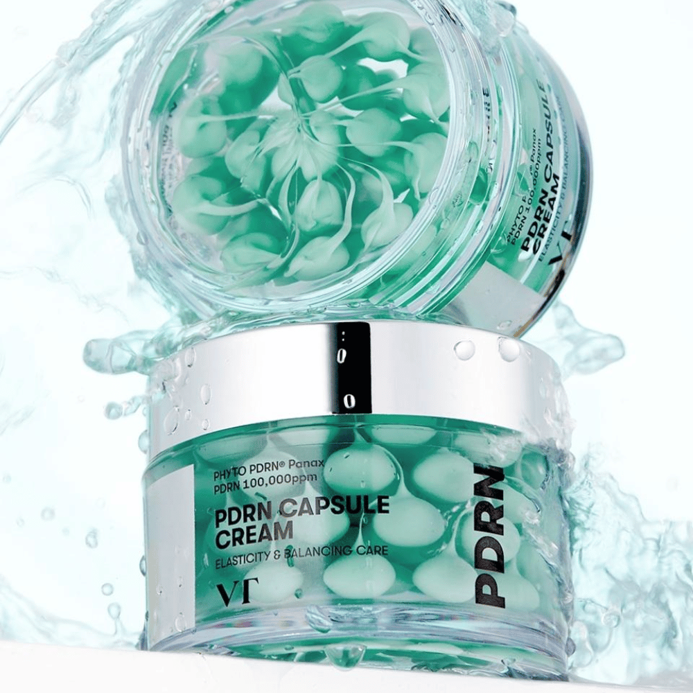Two jars of VT PDRN Capsule Cream stacked with water splashes around. The transparent jars reveal green capsules inside, with the text "Elasticity & Balancing Care" visible on the label.