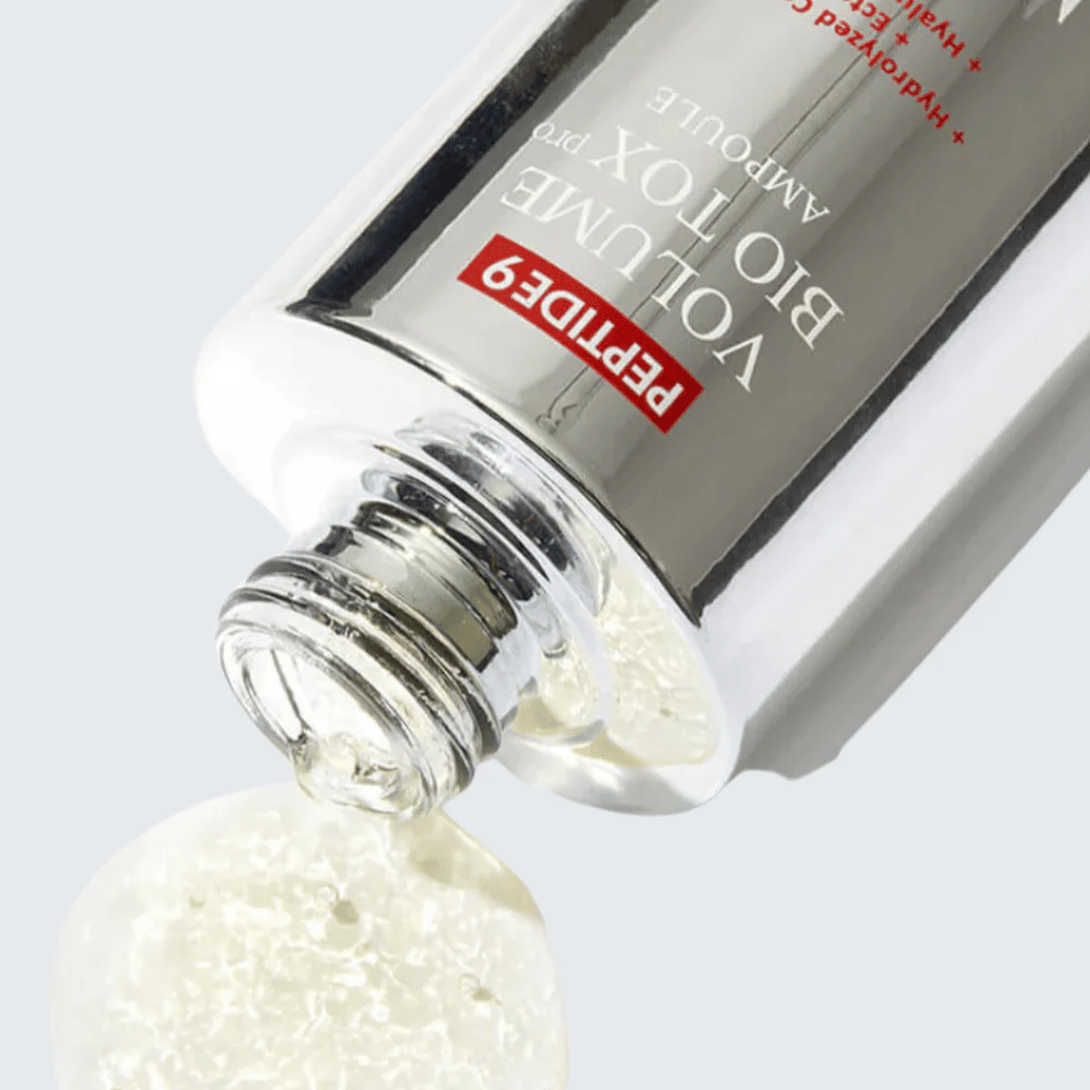 Close-up of MEDI-PEEL Peptide 9 Volume Bio Tox Pro Ampoule being poured. The clear formula with collagen, ectoin, and hyaluronic acid deeply hydrates.