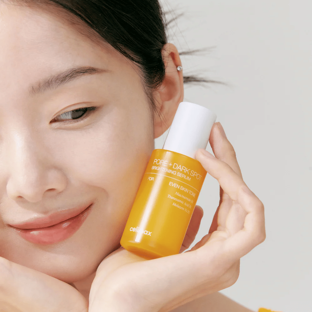 Model holds Celimax Pore + Dark Spot Brightening Serum close to the face, showing radiant skin.