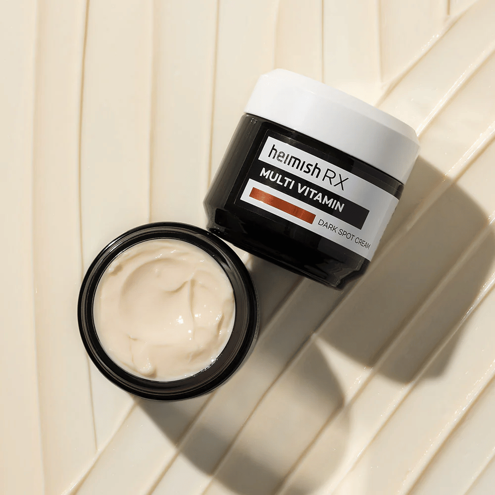 heimish RX Multi Vitamin Dark Spot Cream – a nourishing face cream to reduce dark spots and give the skin a more even tone. The cream's smooth texture is shown in an open jar with elegant packaging.
