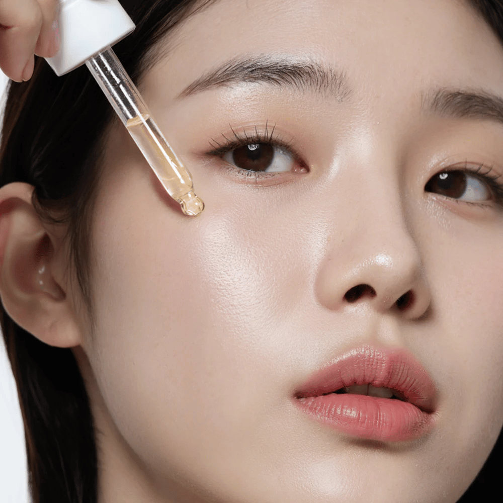 Close-up of a woman with smooth, hydrated skin applying Heimish RX Multi Vitamin 7% Glow Serum with a dropper for extra radiance and nourishment.