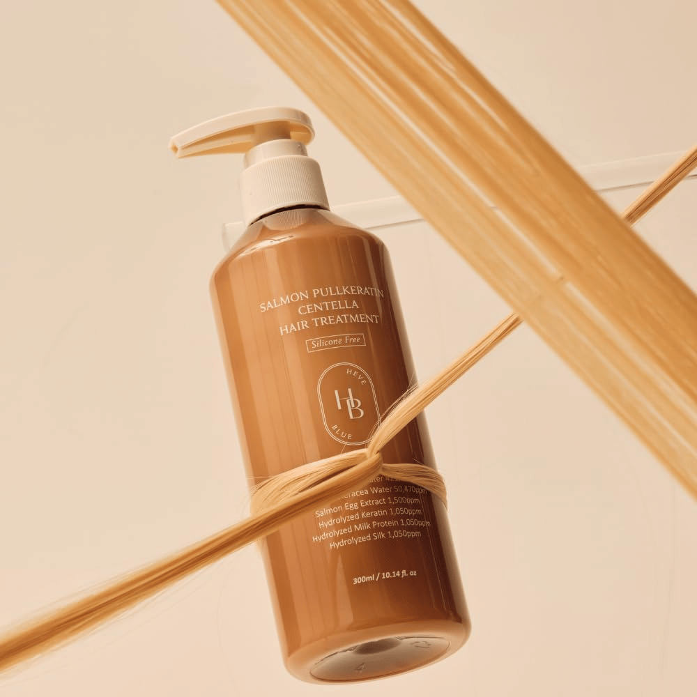 Heveblue Salmon Pullkeratin Centella Hair Treatment in a brown bottle surrounded by strands of hair. The image highlights the nourishing properties of the hair treatment with a focus on shine, strength, and silky-smooth hair.
