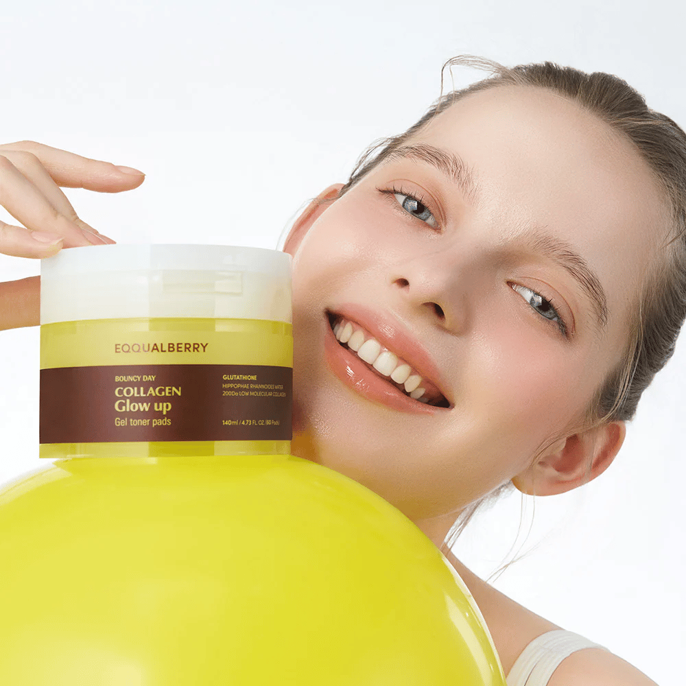 Smiling model holding Bouncy Day Collagen Glow up Gel Toner Pads, which helps to provide a youthful glow and firmness with low molecular collagen and glutathione.
