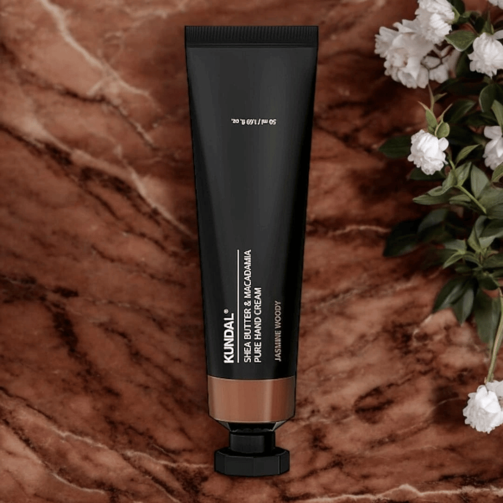 KUNDAL Shea Butter & Macadamia Pure Hand Cream Jasmine Woody placed on marble with flowers – nourishing hand cream that cares for dry hands and gives an elegant jasmine woody scent.