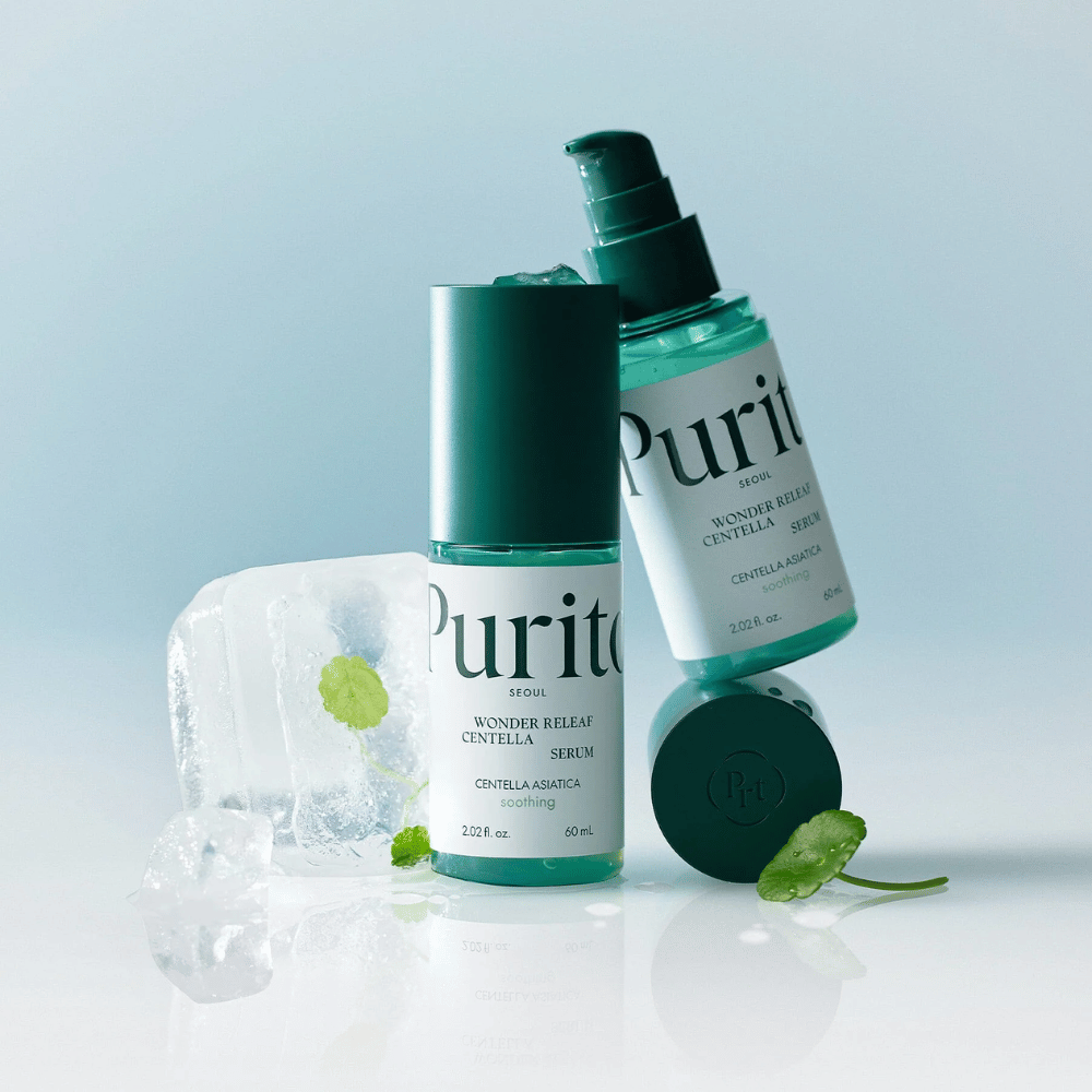 Two bottles of Purito Wonder Releaf Centella Serum, one standing and one lying down, surrounded by ice cubes with centella leaves inside and a loose leaf on a light blue surface.