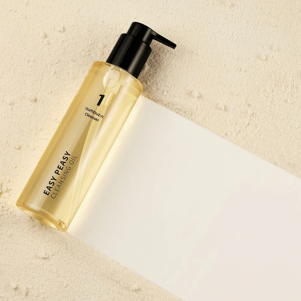 Numbuzin No.1 Easy Peasy Cleansing Oil lying on a sand-colored surface with shadow.