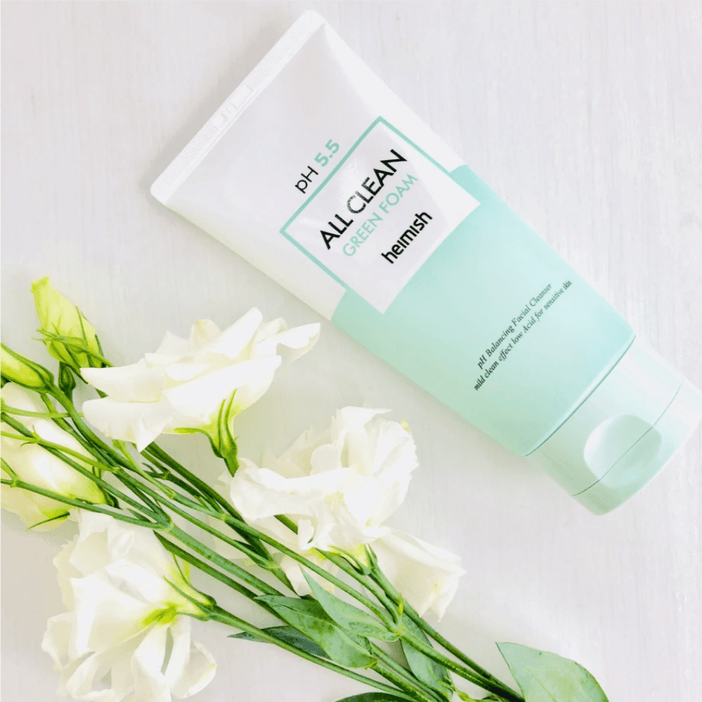 A tube heimish All Clean Green Foam 150ml next to white flowers.